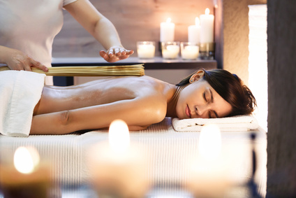 Masseur makes massage to young girl. Woman having bamboo stick massage at day spa